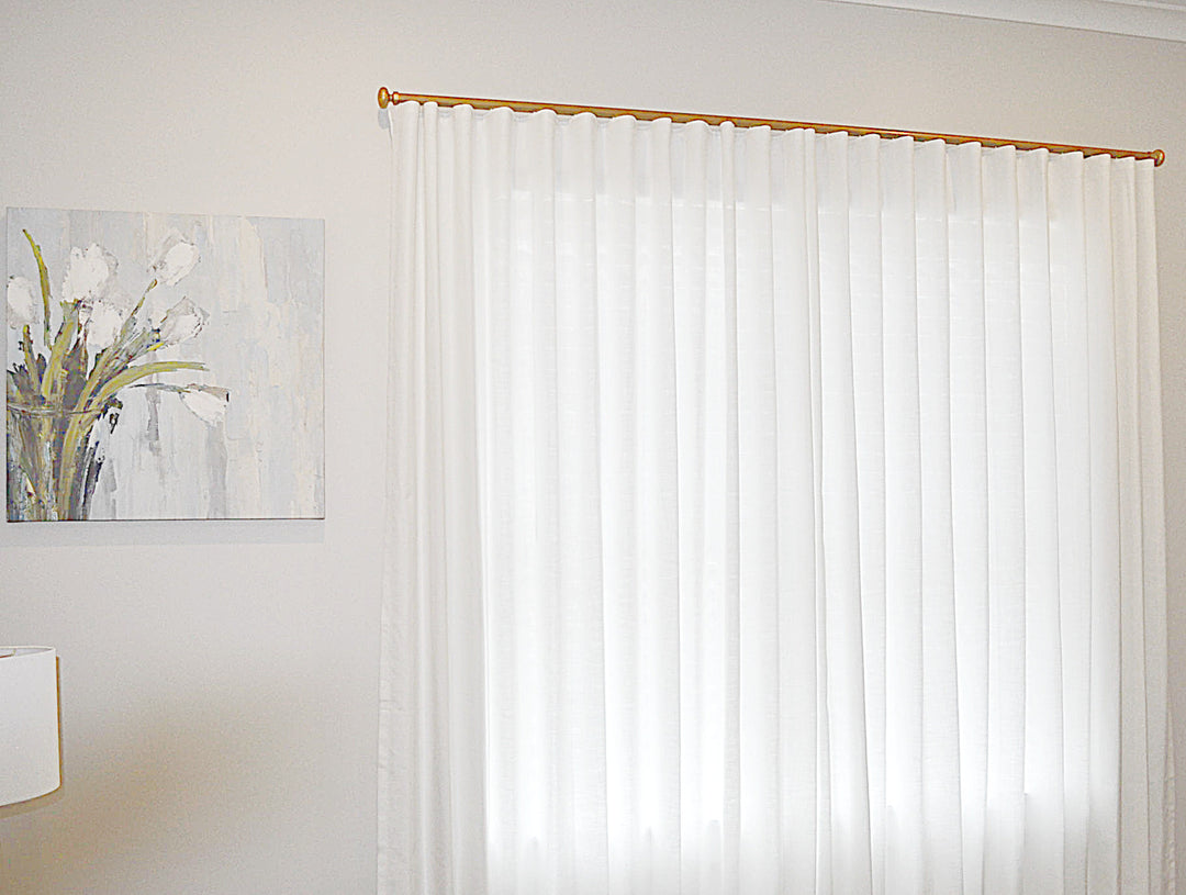 White linen wavefold curtain with a gold rod