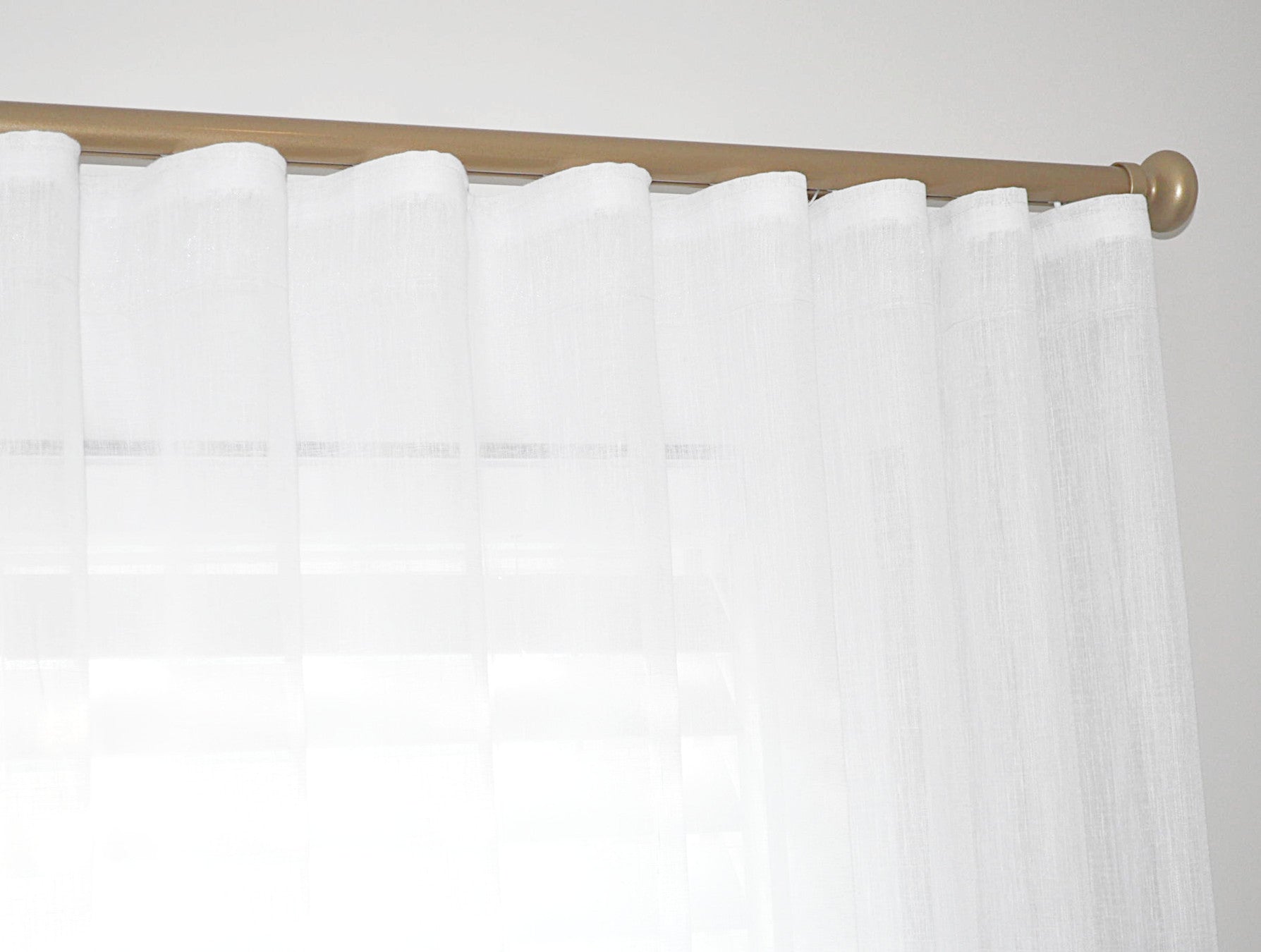 Sheer wavefold curtain panel on gold traverse rod