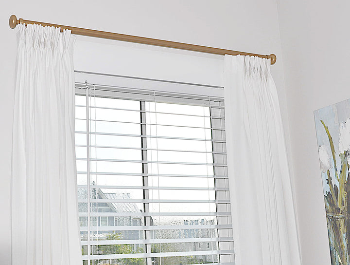 White faux linen pleated panels of gold curtain track with finials